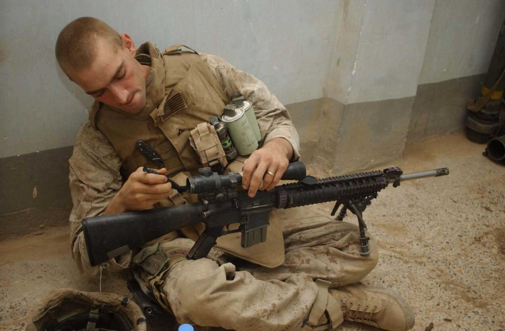 A marine using Lens Pen to clean rifle Scope
